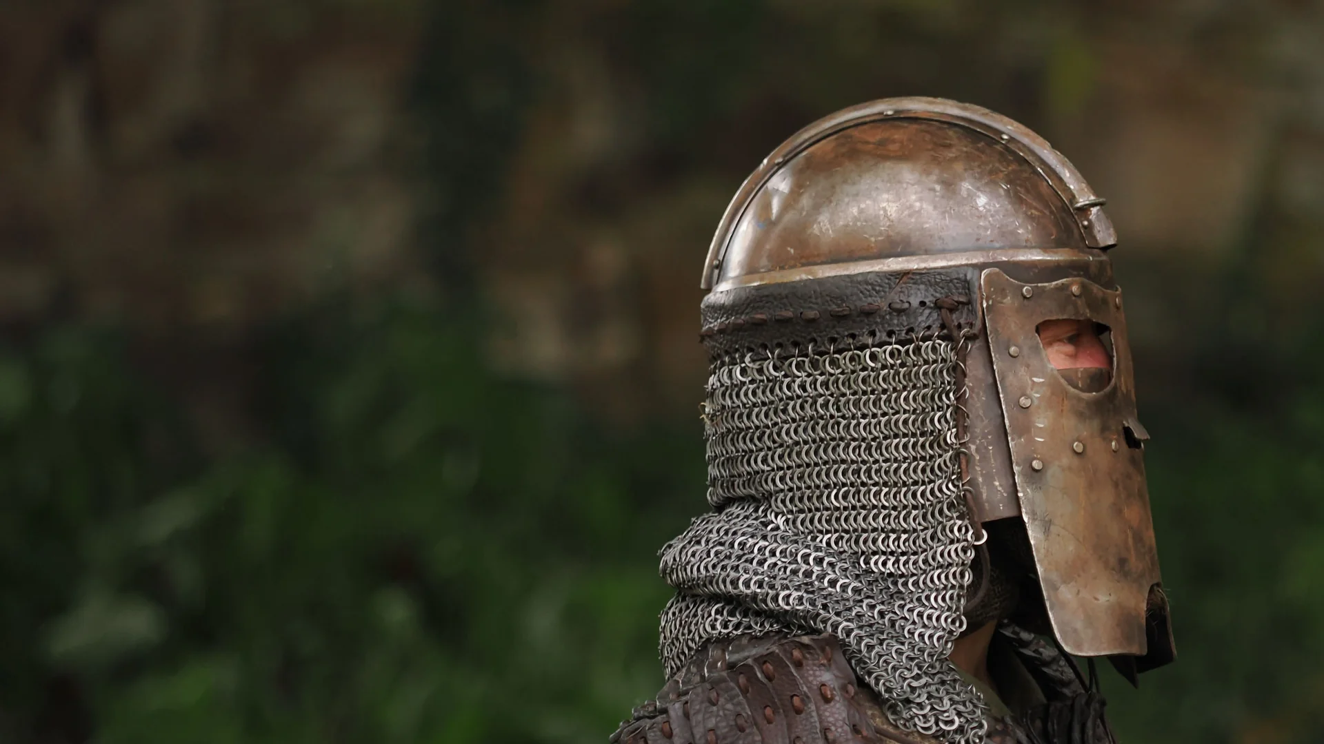 A knight in a medieval helmet and mail coif, side profile, representative of the tournament's knights